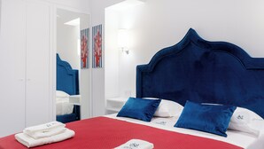 A hotel room with a large bed, white walls, and a red bedspread. There are two blue pillows and a white headboard. - Sorrento Luxury Home (Sorrento)