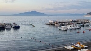 A marina with boats docked, a pier with buildings, and a mountain in the background. - Sorrento Luxury Home (Sorrento)