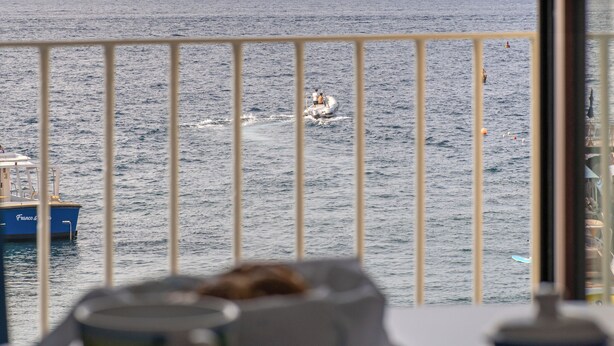 A table with teacups and saucers, a view of the sea with a boat, and a distant mountain. - Sorrento Luxury Home (Sorrento)