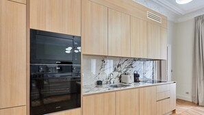 Una cocina moderna con armarios de madera, horno empotrado y encimera de mármol.