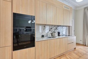 Eine moderne Küche mit Holzschränken, einem eingebauten Backofen und einer Marmorarbeitsplatte.