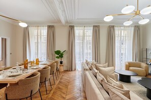 A spacious dining area with a long wooden table set for a meal, surrounded by wicker chairs. - Sublime apartment in the center of Paris (Paris)