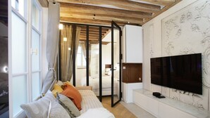 Een moderne slaapkamer met een groot bed, een aan de muur bevestigde televisie en een schuifdeur naar een andere kamer.