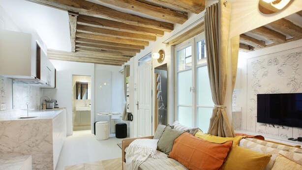 Een moderne woonkamer met een bank, een televisie en een groot raam.