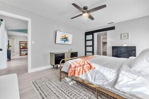 Un dormitorio con cama, ventilador de techo, cómoda y alfombra.
