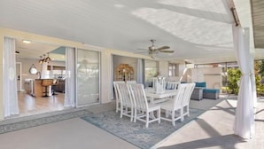 A spacious patio area with a dining table and chairs, a ceiling fan, and a view of the interior through glass doors. - Villa Tarpon Terrace (Cape Coral)