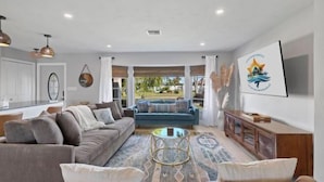 A modern living room with a sofa, coffee table, and a view of the outdoors. - Villa Tarpon Terrace (Cape Coral)