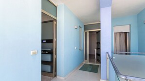 A hotel corridor with light blue walls, a glass railing, and a door leading to a room. - Residence Borgo & Mare (Melendugno)