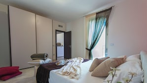 A hotel room with a bed, a chair, a small table with a tray, and a red pillow. - Residence Borgo & Mare (Melendugno)