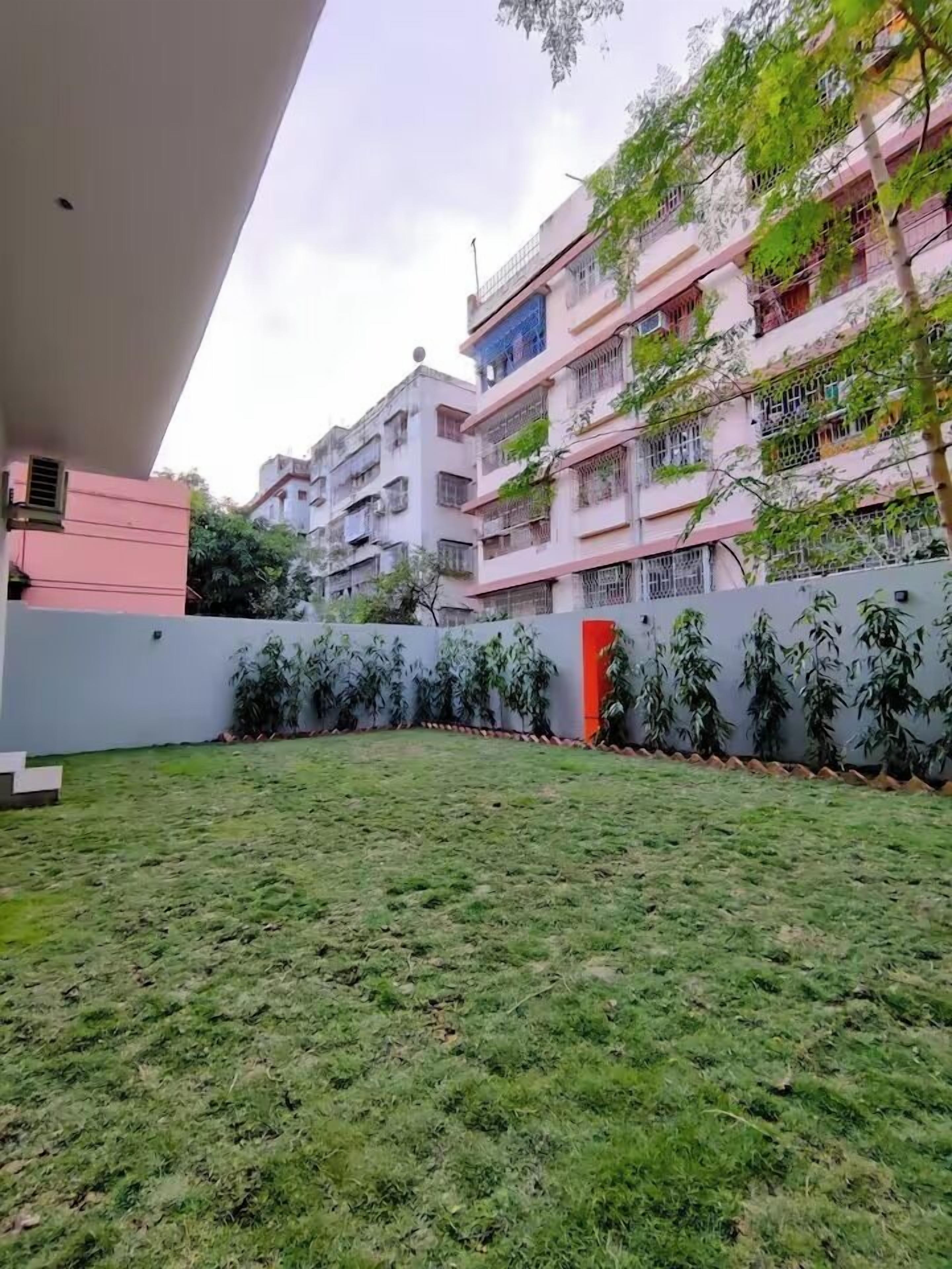 Un quartier résidentiel avec une cour verdoyante, une porte rouge et un immeuble à plusieurs étages doté de balcons.