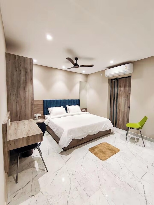 A bedroom with a bed, a desk, a chair, a ceiling fan, an air conditioner, and a wooden accent wall.