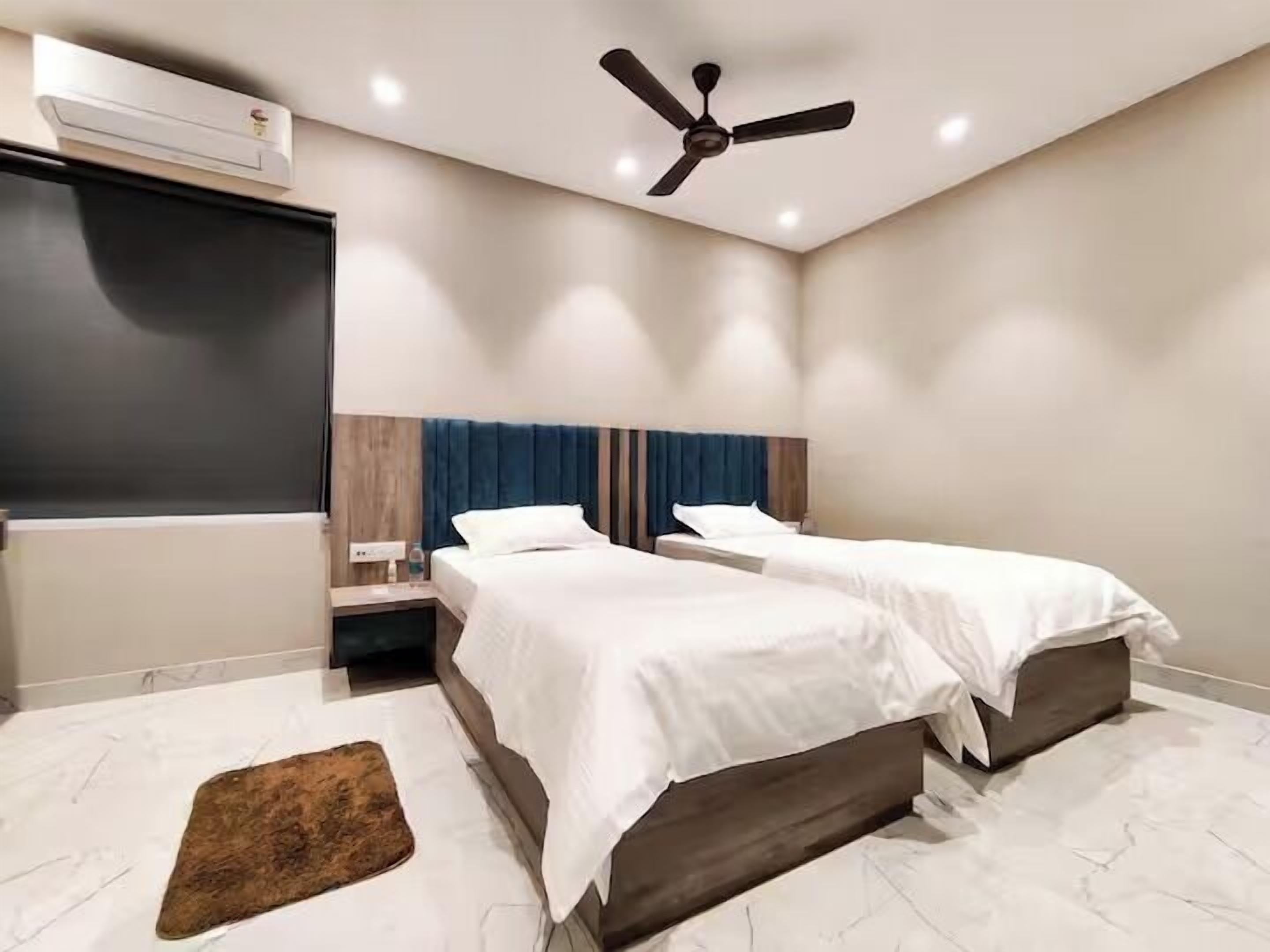A hotel room with two beds, a ceiling fan, an air conditioning unit, and a marble floor.