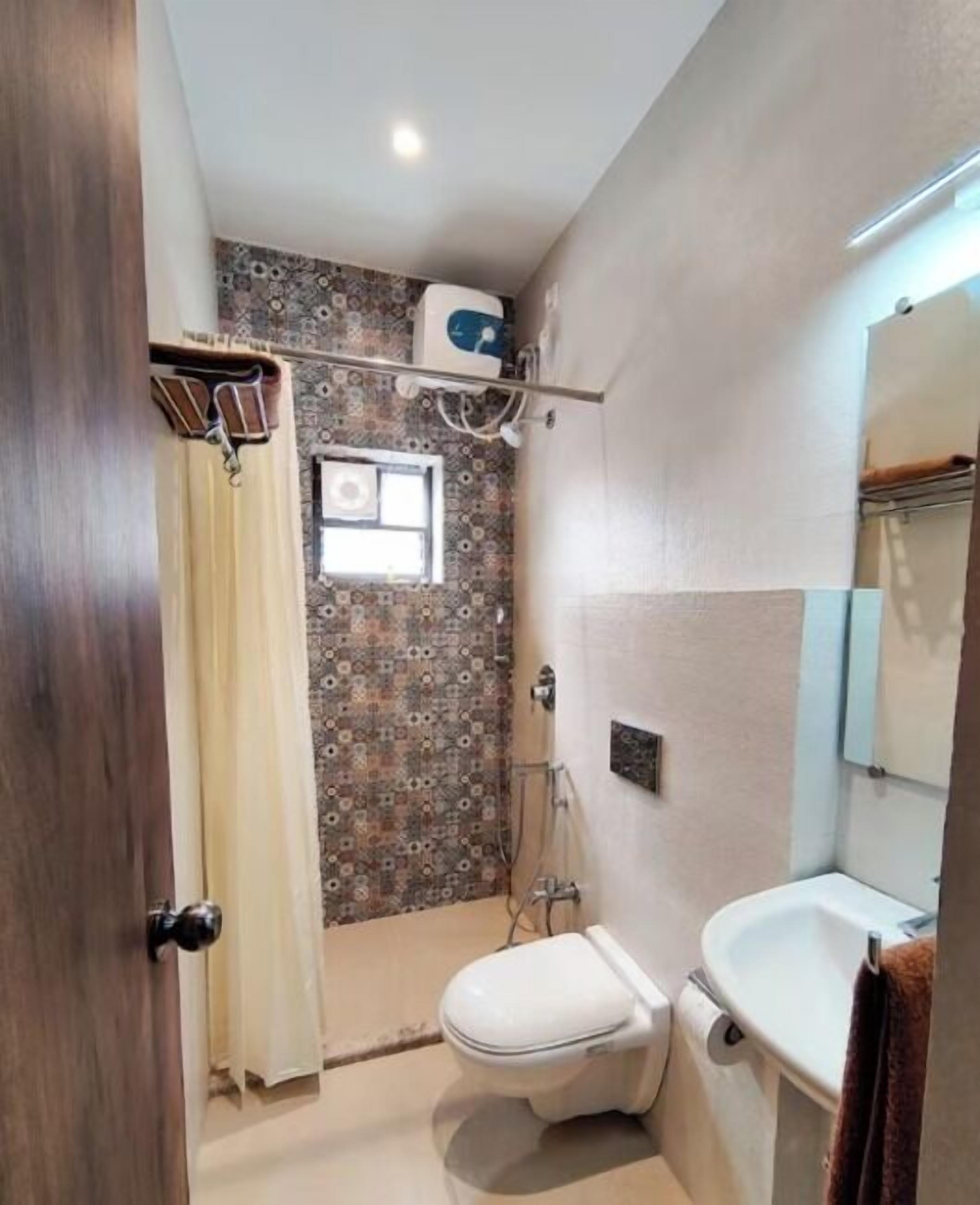 A bathroom with a toilet, sink, shower, and a towel rack.