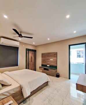 Un dormitorio con una cama, un ventilador de techo, un televisor, un armario de madera y una ventana.