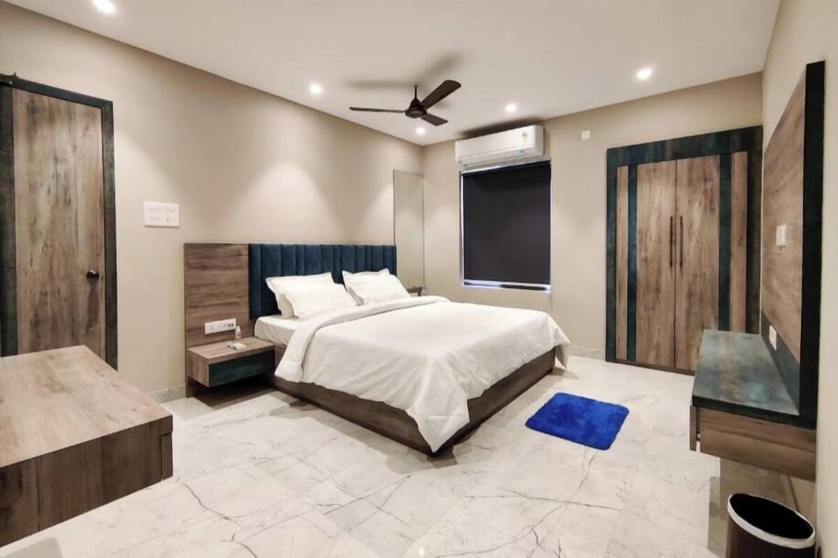Een slaapkamer met een bed, nachtkastjes, een plafondventilator, een airconditioning en een raam.