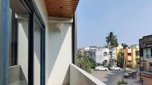 A balcony with a wooden ceiling, large windows, and a view of the street. - Stay by Insata Hospitality - Kolkata (Bidhannagar)