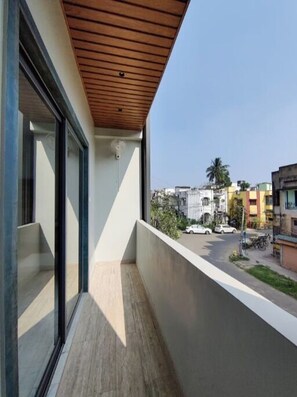 Un balcone con soffitto in legno, ampie finestre e vista sulla strada.