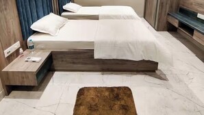 A modern bedroom with two beds, a ceiling fan, a wooden wardrobe, and a marble floor. - Stay by Insata Hospitality - Kolkata (Bidhannagar)