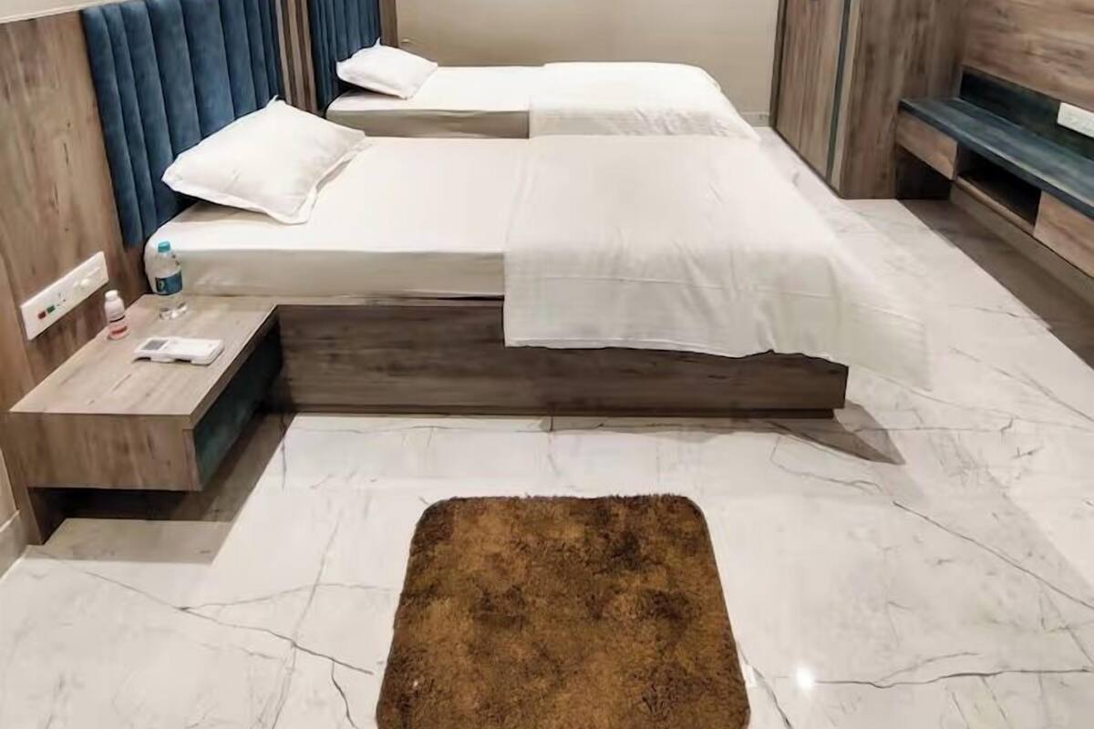 Een moderne slaapkamer met twee bedden, een plafondventilator, een houten garderobe en een marmeren vloer.