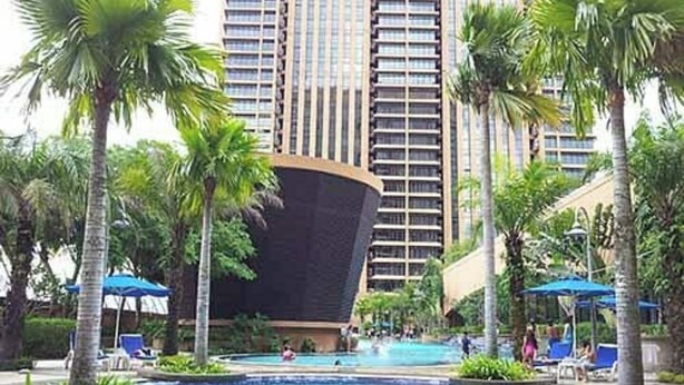 A swimming pool surrounded by palm trees and lounge chairs, with tall buildings in the background. - East Service Suite Times Square KL (Kuala Lumpur)