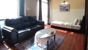 A living room with a black sofa, a white sofa, a small round table with a tissue box, and a patterned rug. - East Service Suite Times Square KL (Kuala Lumpur)