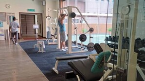 A gym with weightlifting equipment, a bench, and a person exercising. - East Service Suite Times Square KL (Kuala Lumpur)