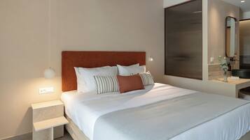 Habitación de hotel moderna con una cama grande, una mesita de noche, un espejo y una pequeña mesa con un florero.