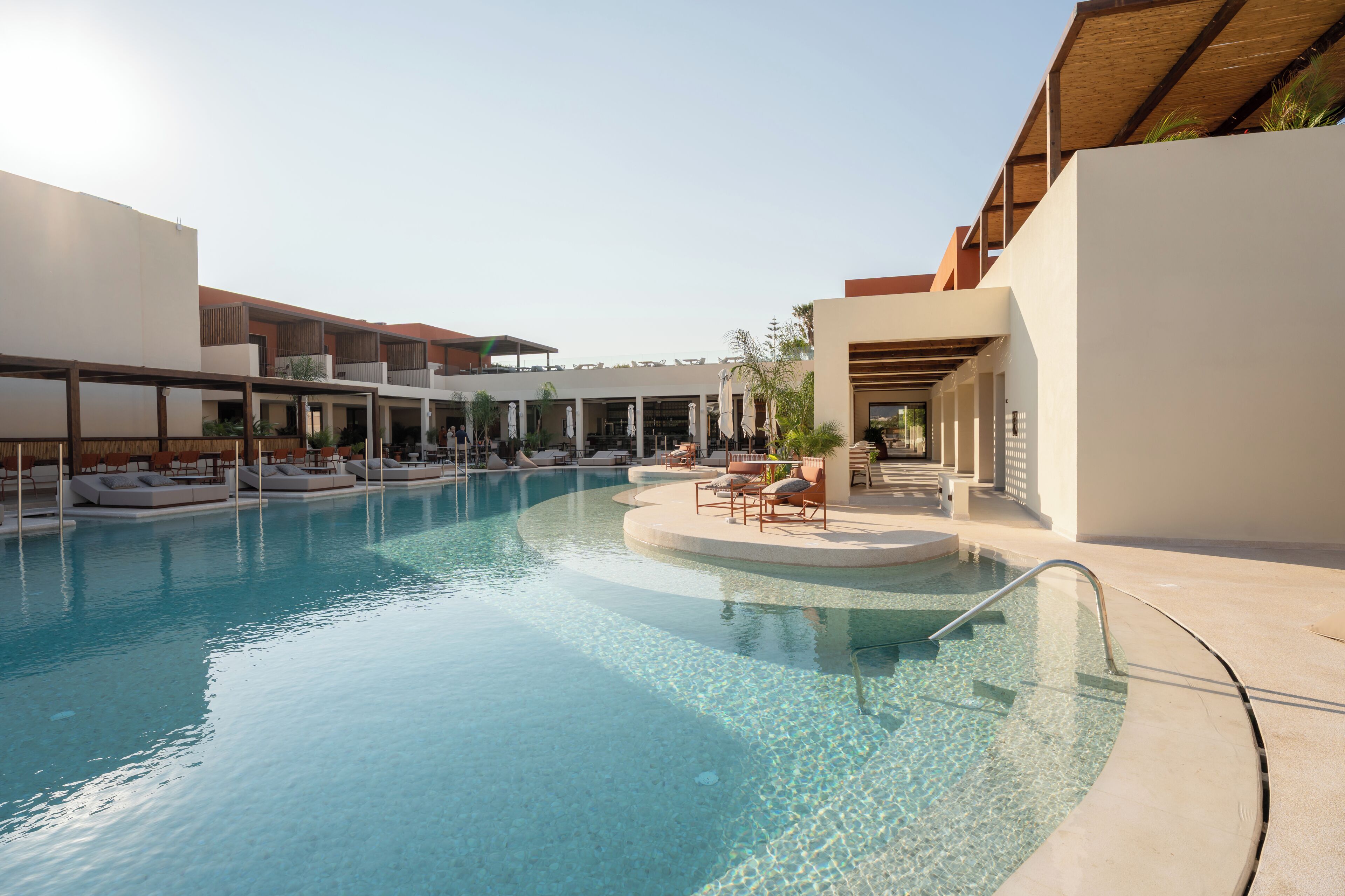 Una piscina con sillones de descanso y una zona de estar techada.
