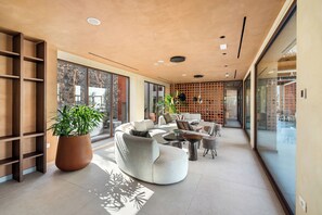Un interior moderno con un sofá curvo, una planta en maceta y una zona de estar con pared de vidrio.