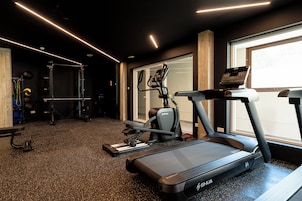 Un gimnasio con cintas de correr, una banca para pesas y equipo de ejercicio.