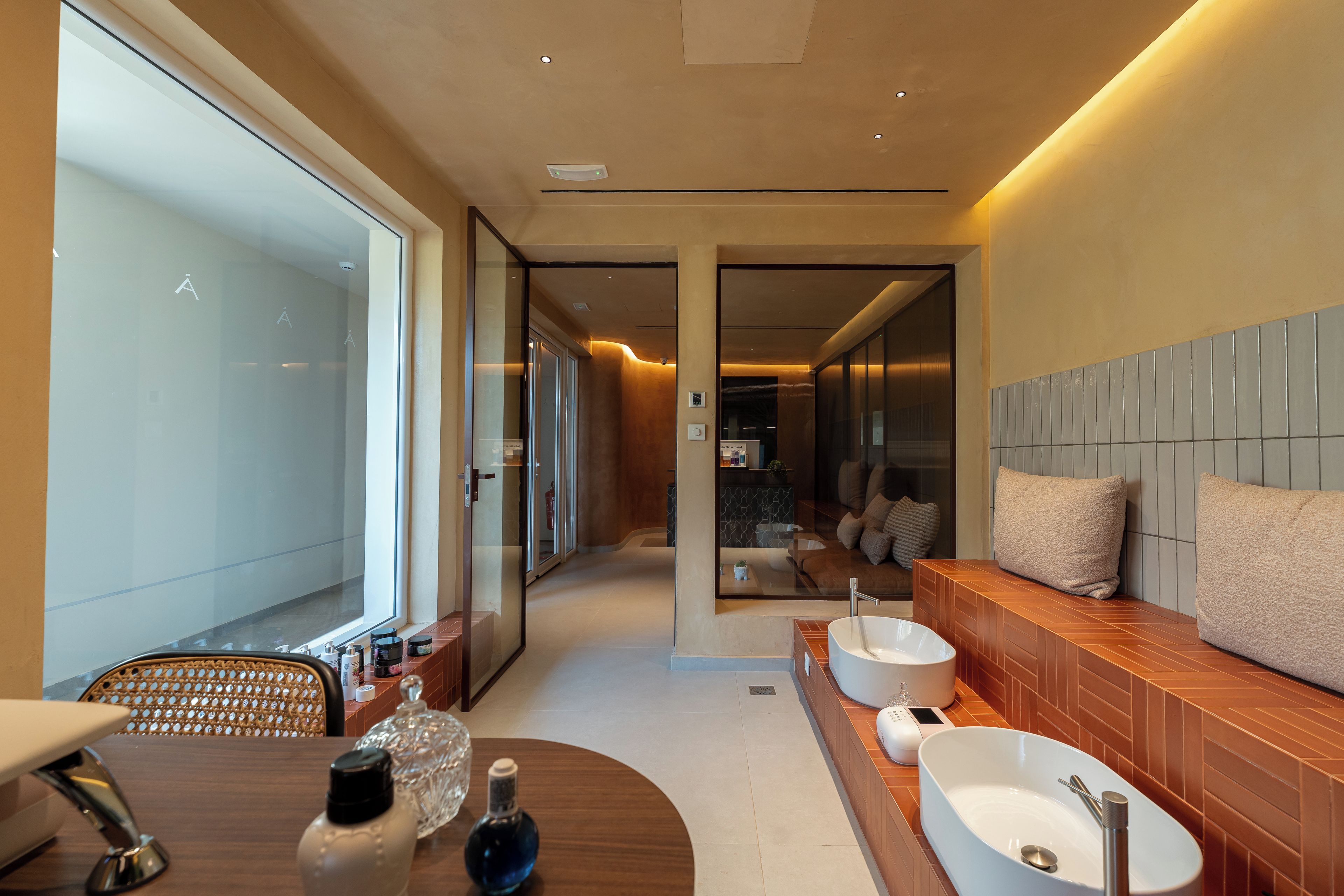 Un baño moderno con una bañera independiente, un tocador con lavamanos y una zona de estar con sofá y cojines.