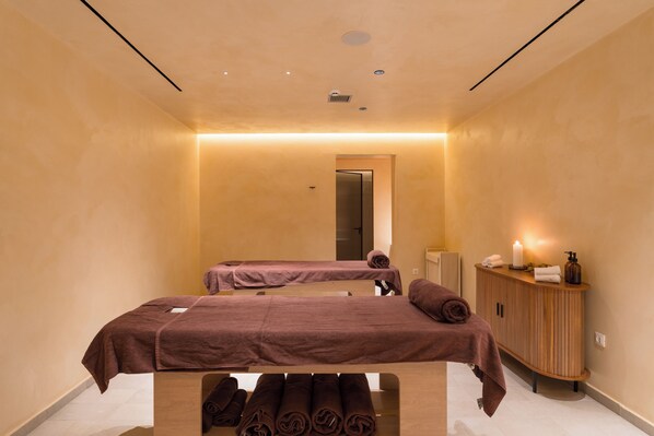 A spa room with two massage tables, a wooden cabinet with toiletries, and a mirror. - ARATO by E•GEO, Adults Only (Kos)