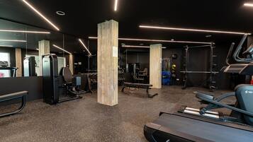 A gym with exercise equipment, a treadmill, and a mirrored wall.