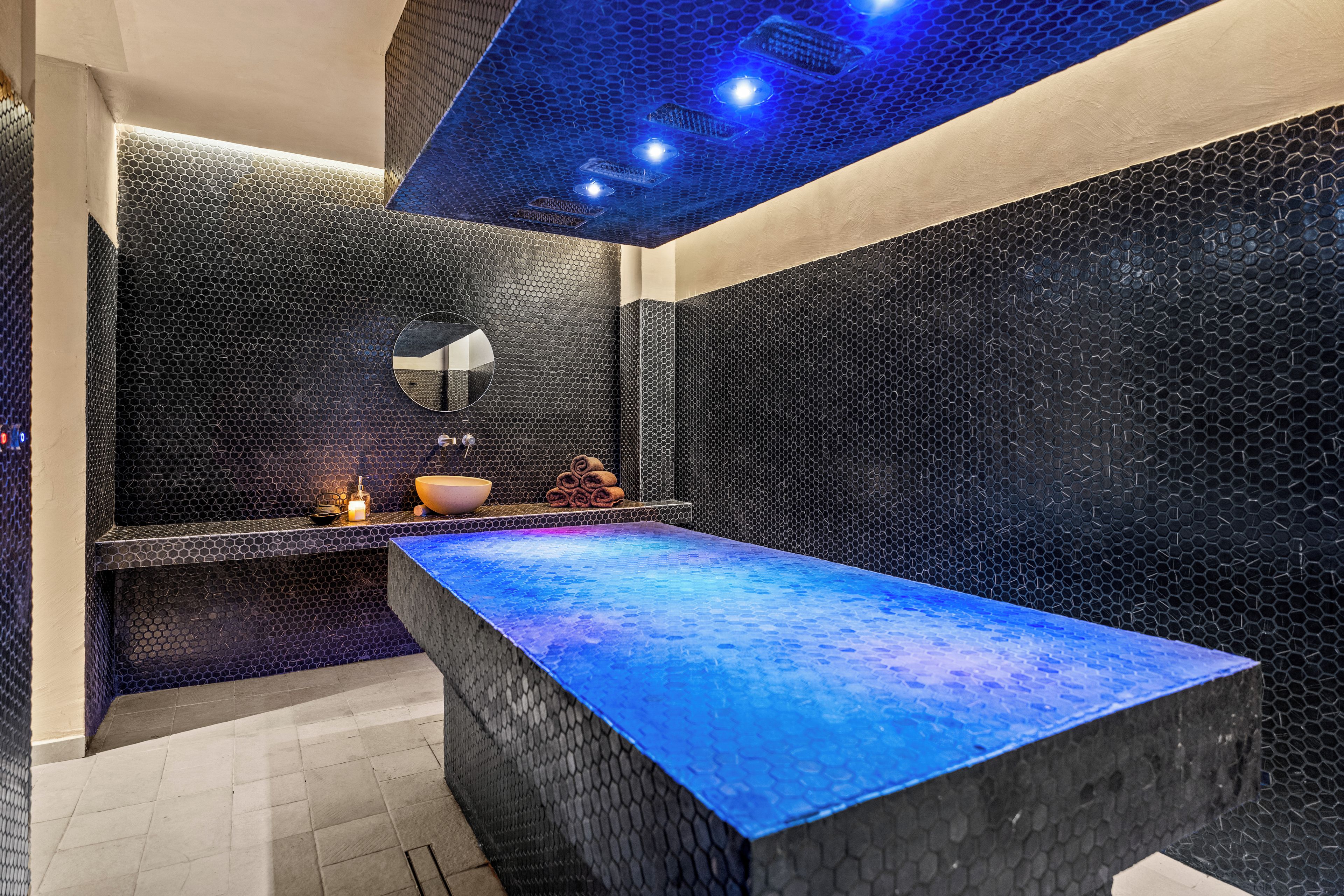 Un baño moderno con un lavabo rectangular grande, un espejo y una encimera iluminada con luz azul.