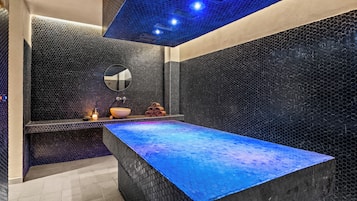 Un baño moderno con un lavabo rectangular grande, un espejo y una encimera iluminada con luz azul.