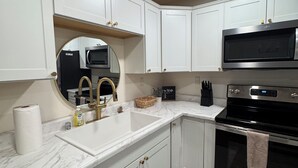 A modern kitchen with white cabinets, a stainless steel dishwasher, a black oven, and a microwave. - New! Aurora Viewing, 3 mins from airport, Prime Location (Fairbanks)