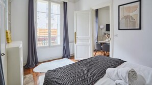 A hotel room with a bed, a desk, and a chair. - Eiffel Tower Terrace Apartment (Paris)