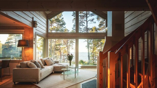 Un salon chaleureux avec une grande fenêtre donnant sur une forêt et un lac.
