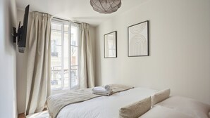 A bedroom with a bed, a window with curtains, and two framed pictures on the wall. - New apartment Center of Paris/Le Marais (Paris)