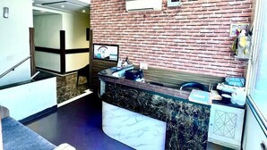 A modern kitchen with a brick backsplash, a marble countertop, and a ceiling fan. - Hotel Woodcrest (Zirakpur)