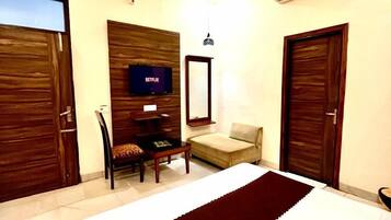 Habitación de hotel con cama, escritorio con televisor, silla, sofá y dos puertas.