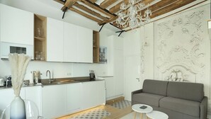 A modern kitchen with white cabinets, a wooden ceiling, and a chandelier. - Charming  Apartment Le Marais Center of Paris (Paris)