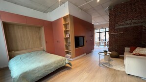 A modern bedroom with a bed, built-in TV, and a brick wall.