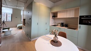 A modern kitchen with built-in appliances, a dining area with a table and chairs, and a small seating area with a sofa and coffee table.