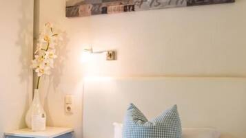 A bedroom with a bed, a nightstand, a vase with flowers, and a wall art piece.