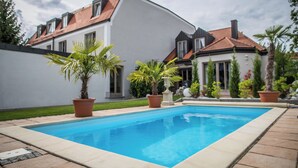 A modern house with a swimming pool, surrounded by potted plants and a well-maintained lawn. - Hotel Domizil (Ingolstadt)