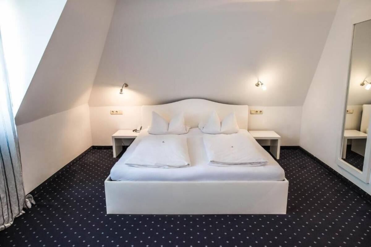 A bedroom with a large bed, two bedside tables, and a mirror on the wall.
