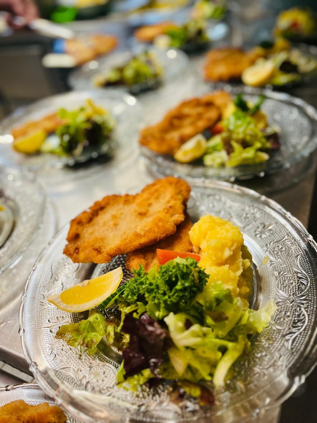 A buffet with various dishes including breaded cutlets, mashed potatoes, and a salad with mixed greens.