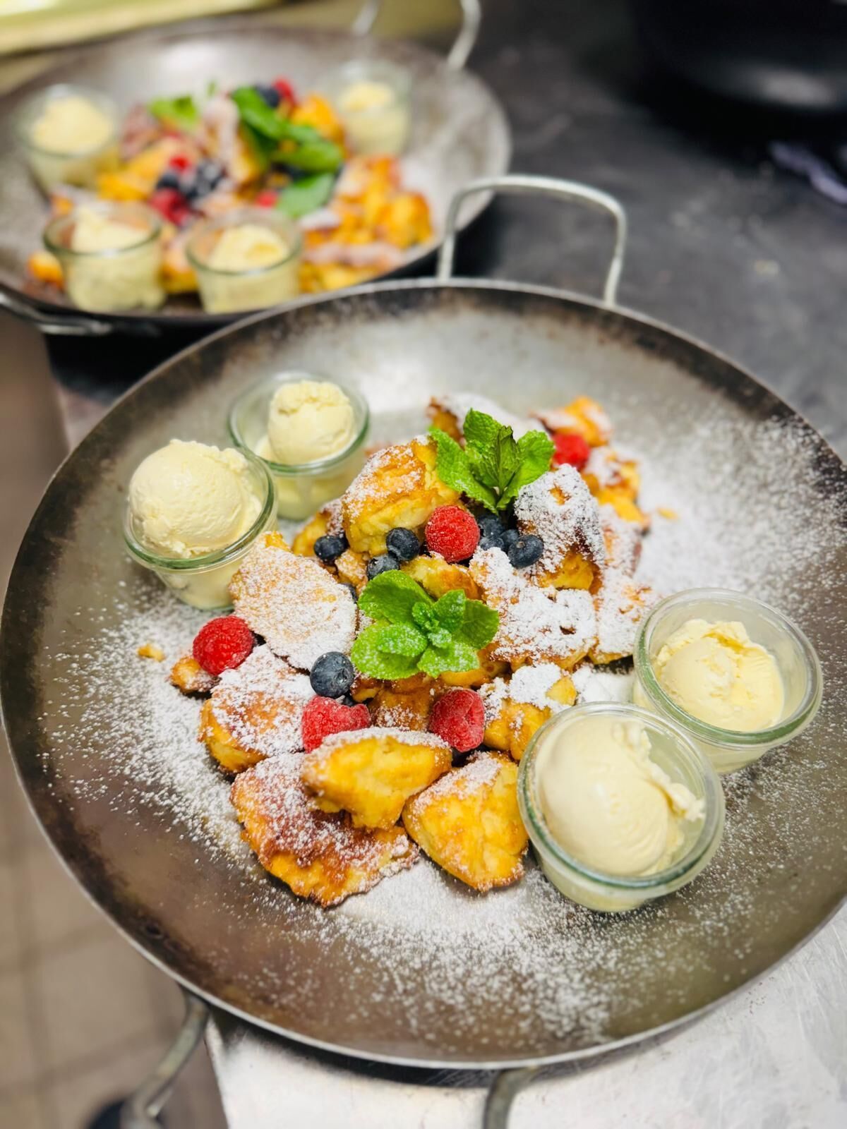 Ein Desserteller mit Pfannkuchen, Beeren und Eis.
