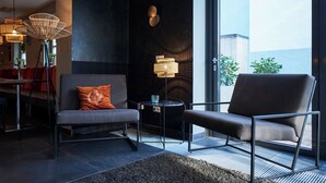 A modern living room with a sofa, armchair, and floor lamp. - Hotel Domizil (Ingolstadt)